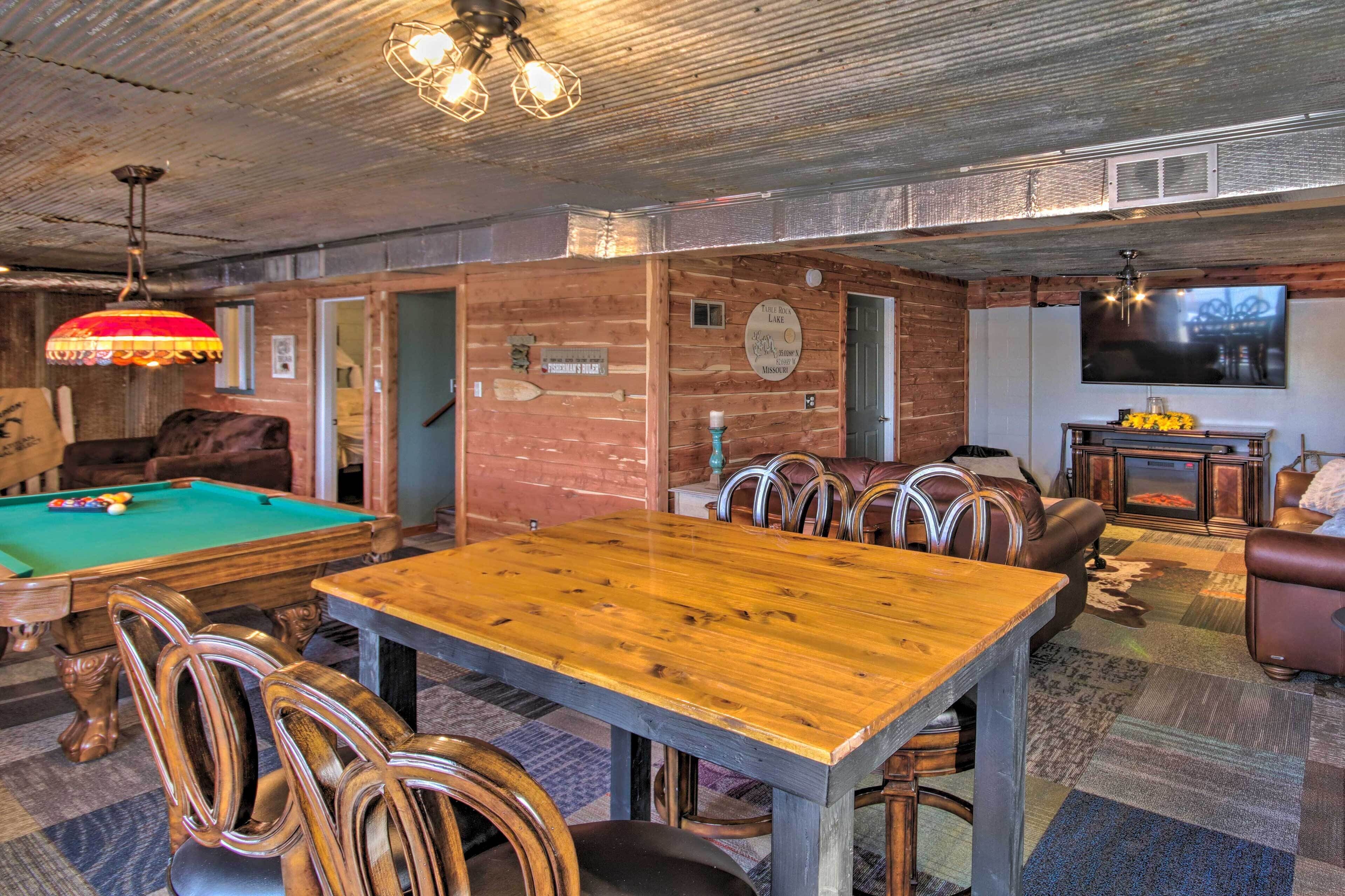 Un espace intérieur accueillant, doté d’une table de billard, d’une table à manger en bois, de fauteuils en cuir et d’un téléviseur.