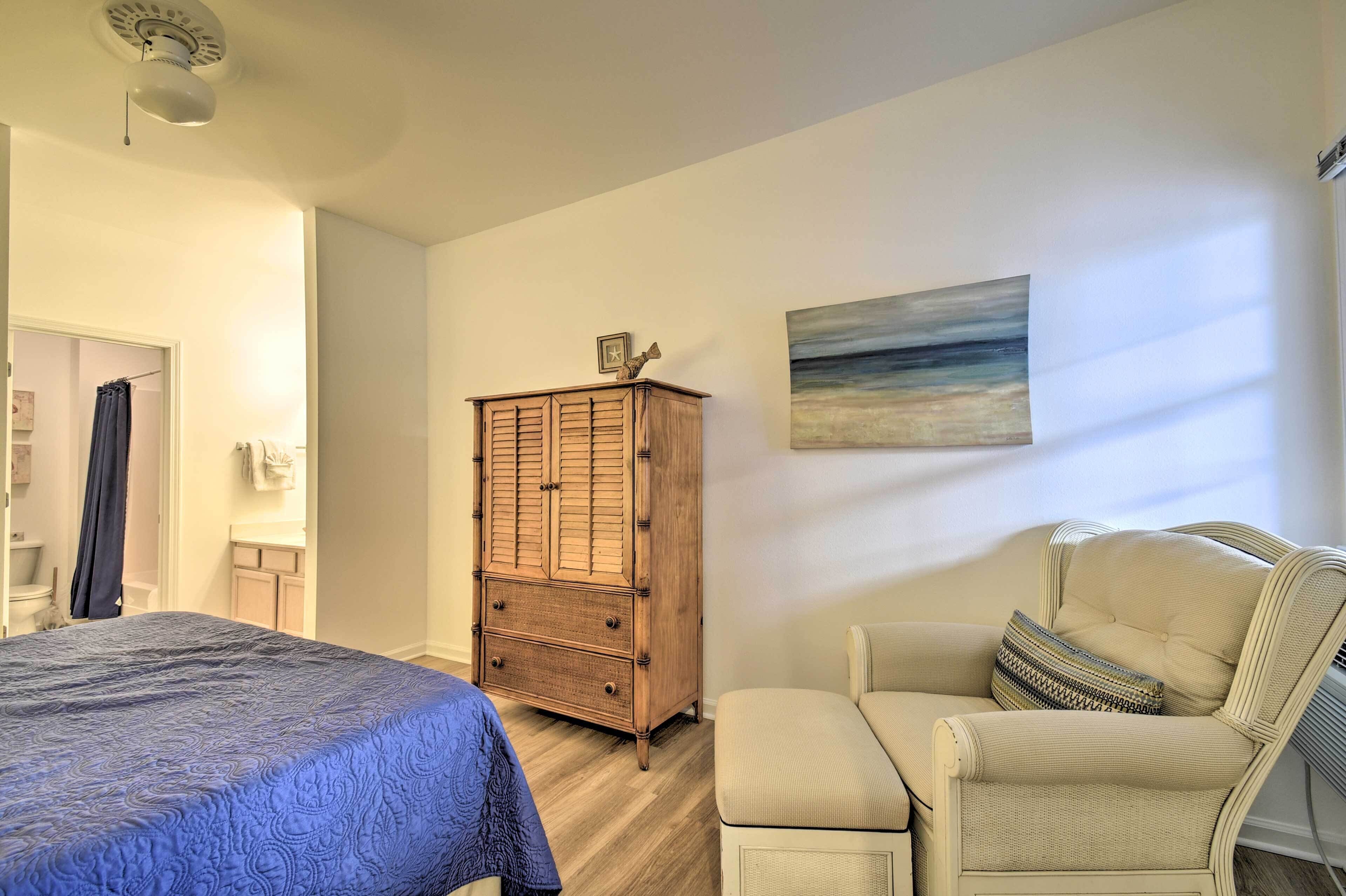 A bedroom with a bed, a wooden cabinet, a chair, and a painting on the wall.