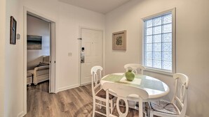 A dining area with a round table, white chairs, and a window with frosted glass. - Sunset Beach Retreat - Monthly Rentals Welcome! (Sunset Beach)