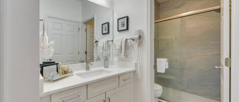A modern bathroom with a large mirror, white sink, and a glass shower enclosure.