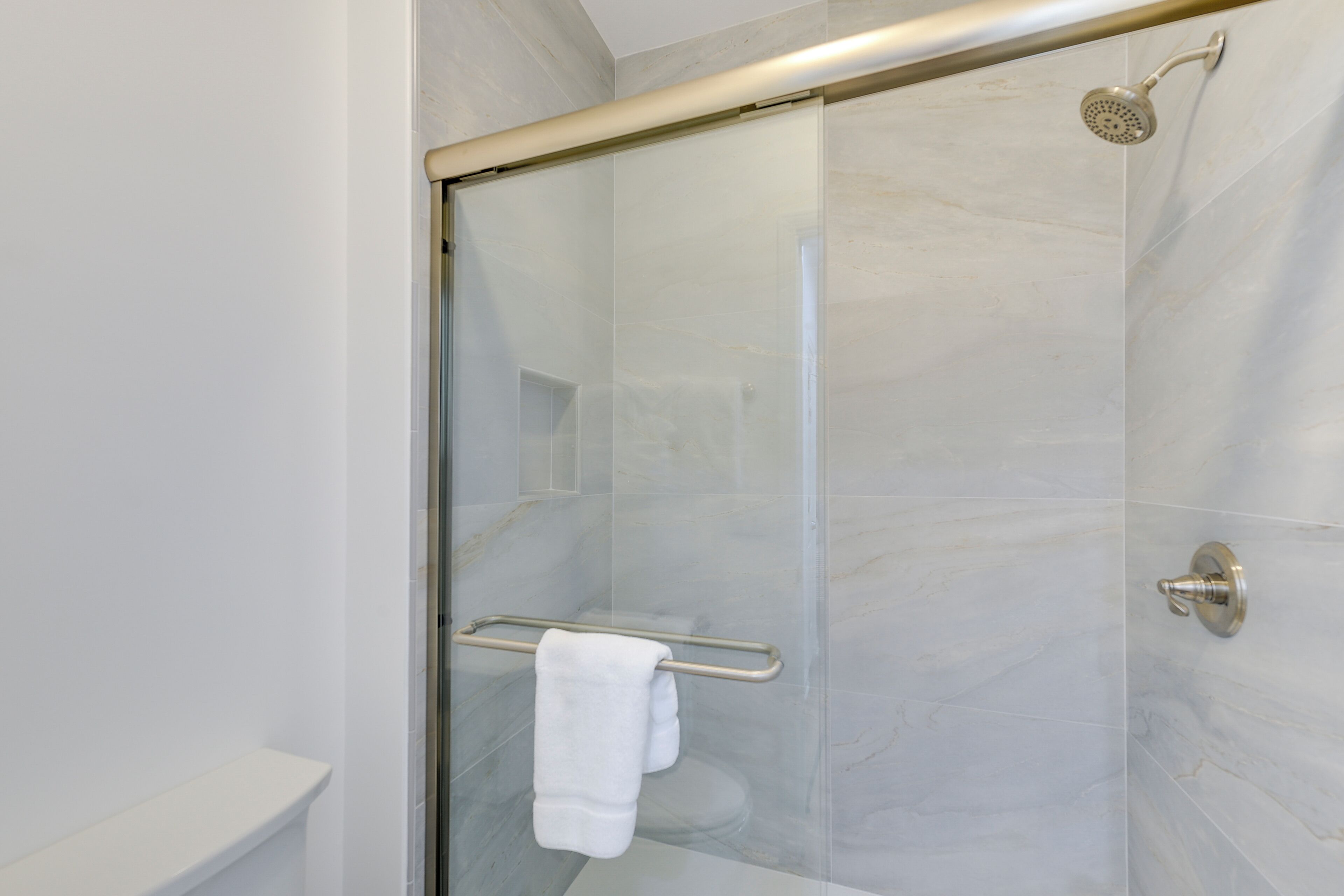 Een moderne badkamer met een douchecabine van glas, een wit toilet en een handdoekrek.