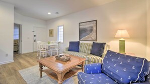A living room with a sofa, coffee table, and a dining area with chairs and a table. - Sunset Beach Retreat - Monthly Rentals Welcome! (Sunset Beach)