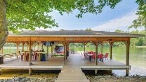 A wooden dock leading to a covered picnic area with tables and chairs, overlooking a calm lake. - Lake Anna Home w/ Dock & Private Shoreline! (Bumpass)