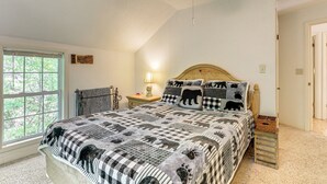 Ein Schlafzimmer mit Bett, Fenster, Nachttisch und Lampe.