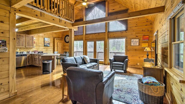L’intérieur de cette vaste cabane en rondins comprend un coin repas, une cuisine et un salon aménagés avec des canapés en cuir et un panier en osier.