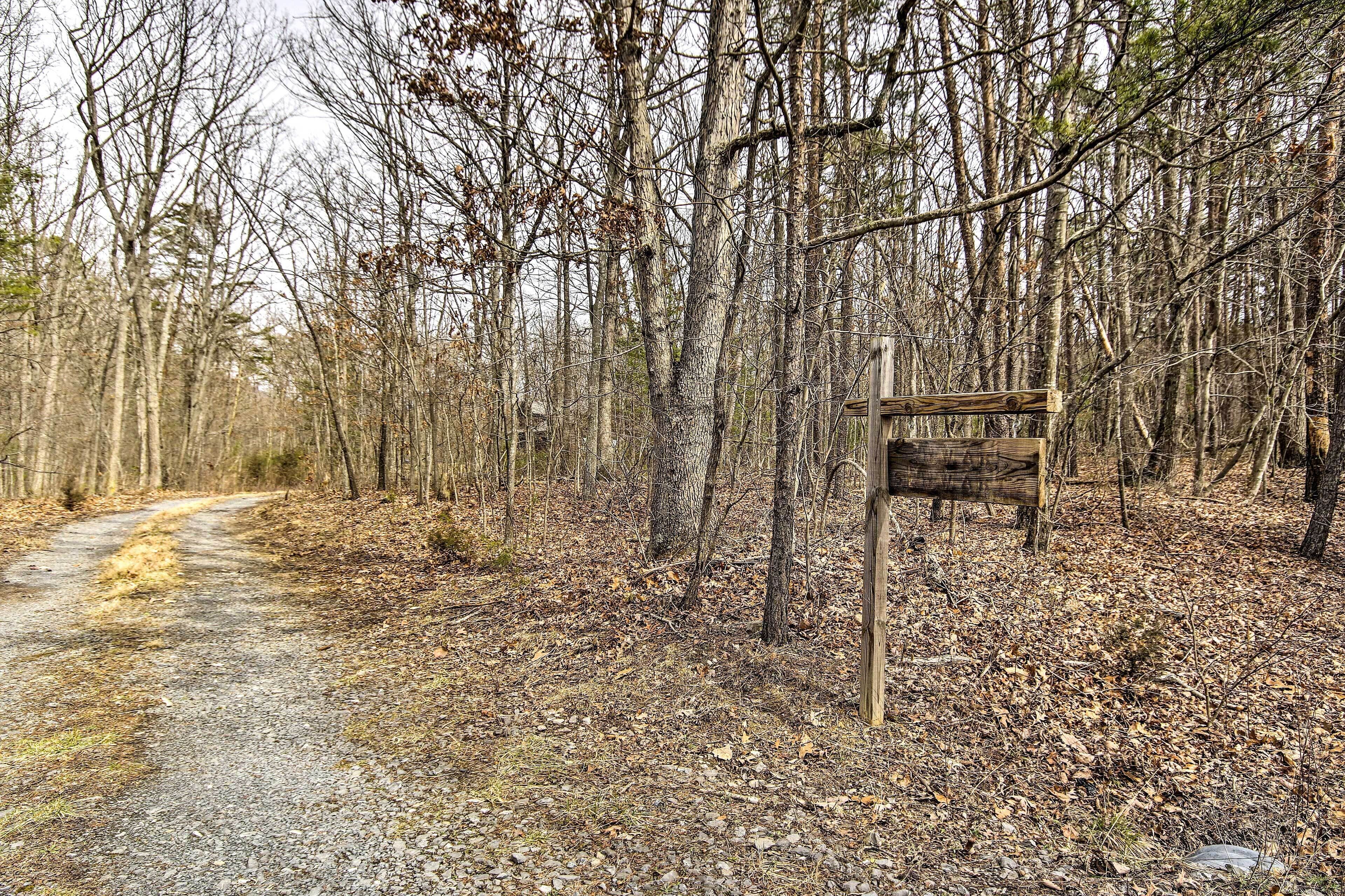 A gravel path in a wooded area with a wooden signpost.