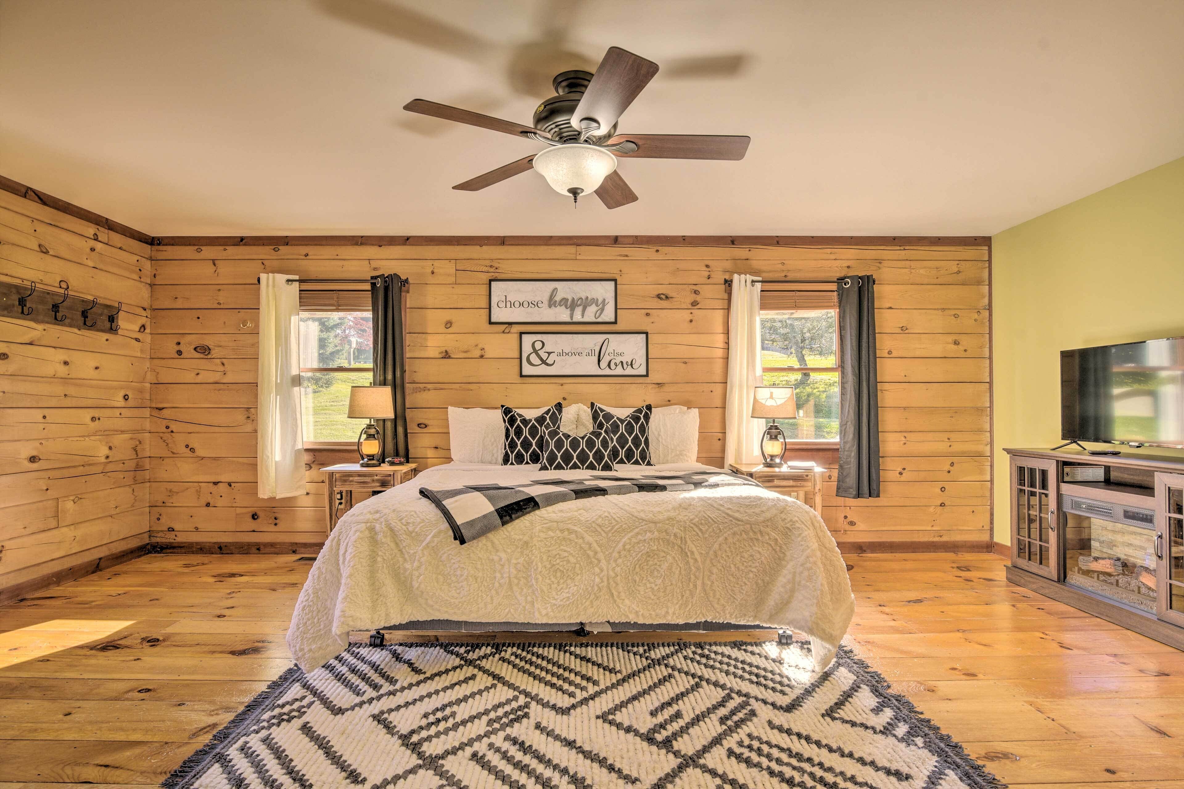 Ein Schlafzimmer mit einem Bett, einem Deckenventilator, einem Fernseher und einem Kamin.