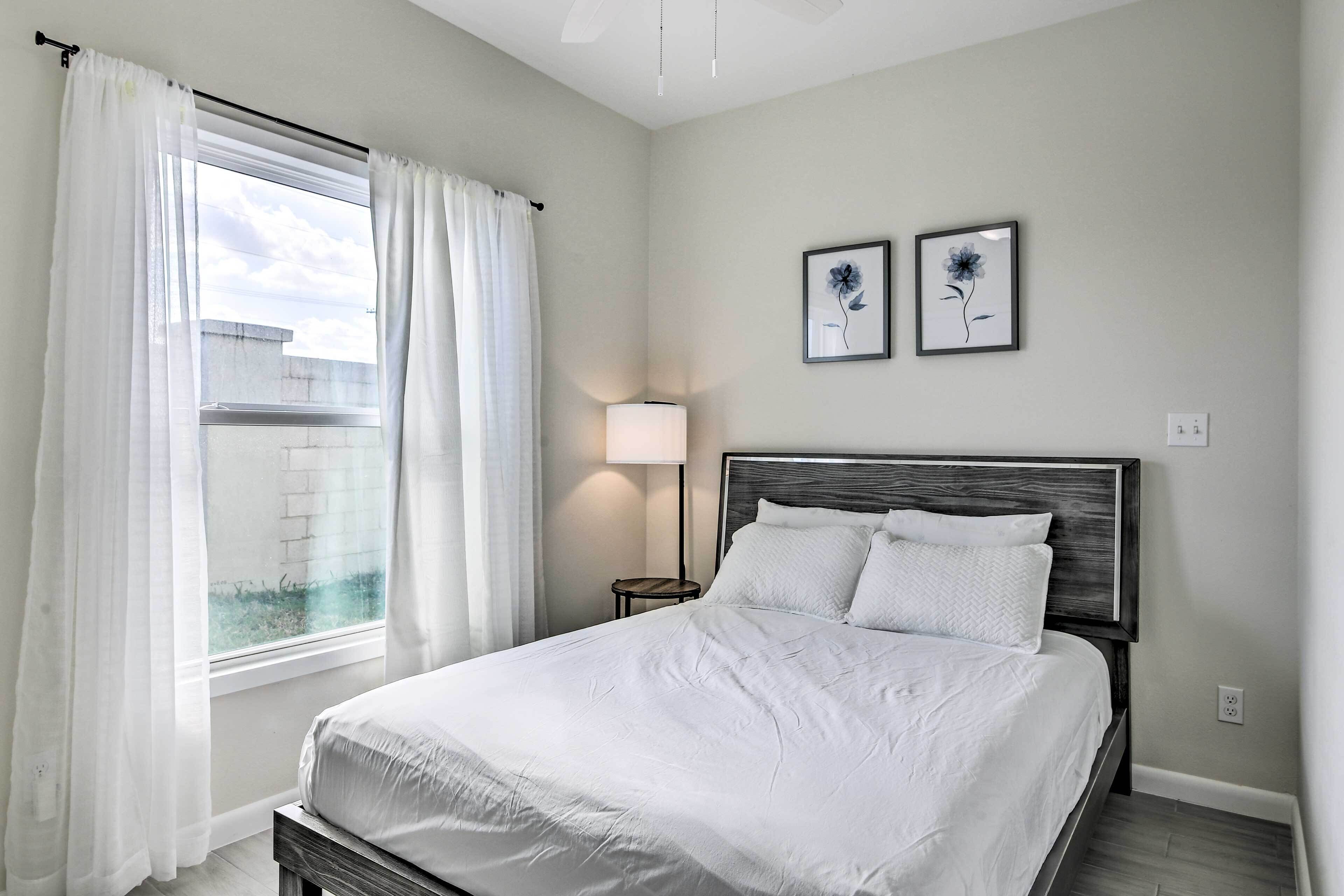 A bedroom with a bed, a nightstand, a lamp, and two wall-mounted flower paintings.