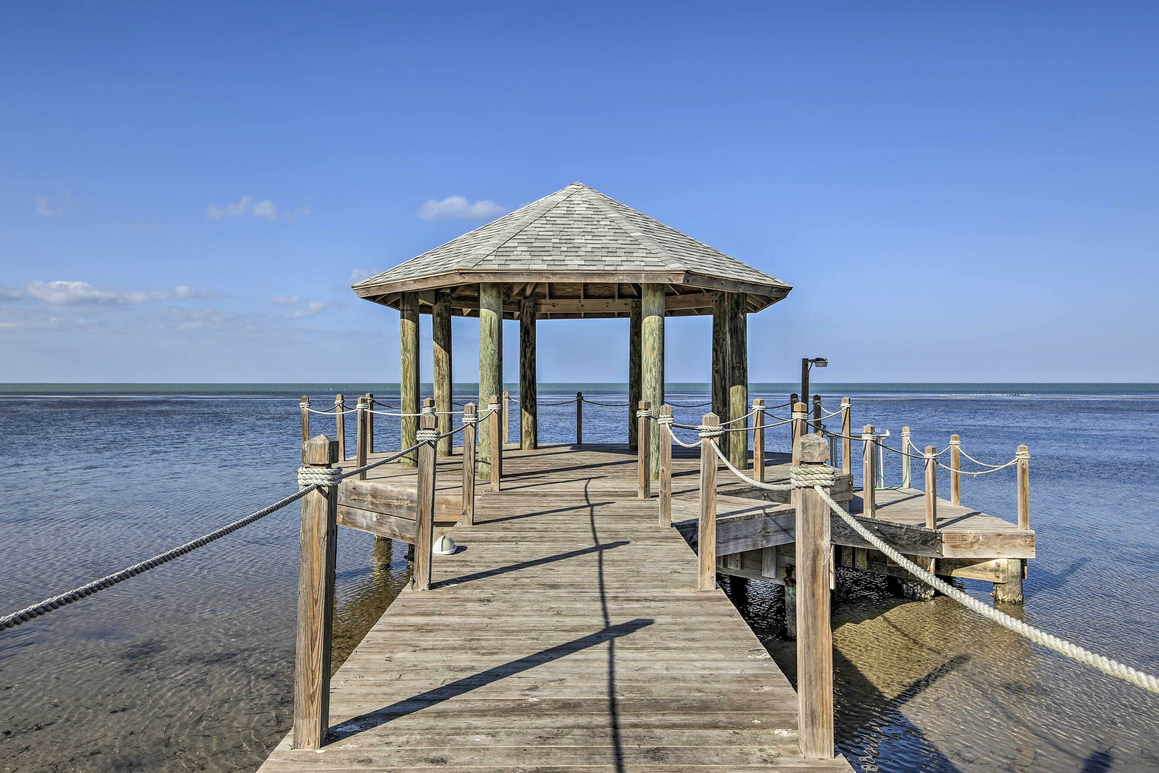 A wooden pier leading to a gazebo with a clear view of the water.