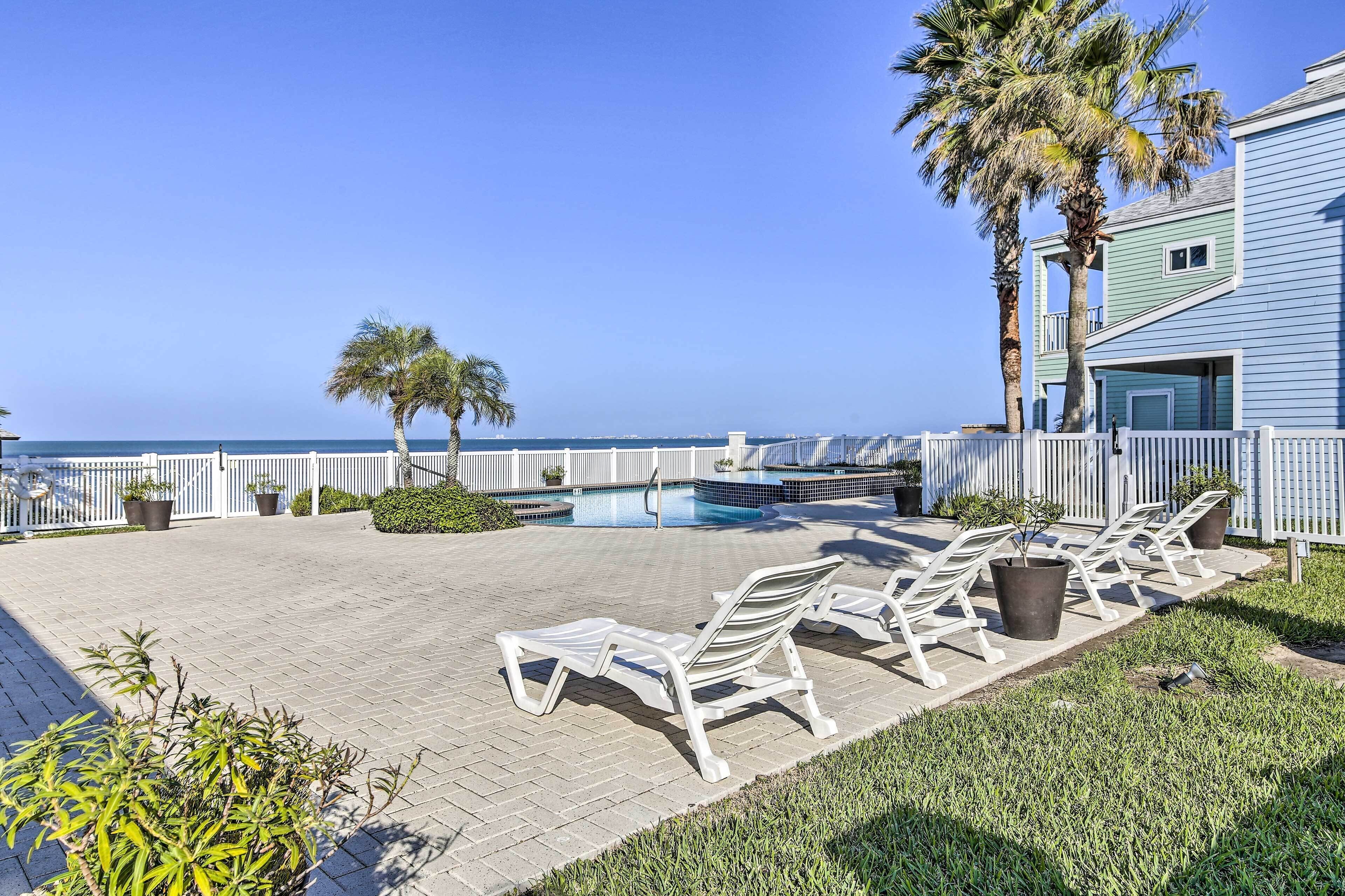A poolside area with lounge chairs, a small pool, and a view of the ocean.