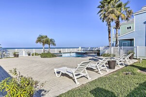 A poolside area with lounge chairs, a small pool, and a view of the ocean.