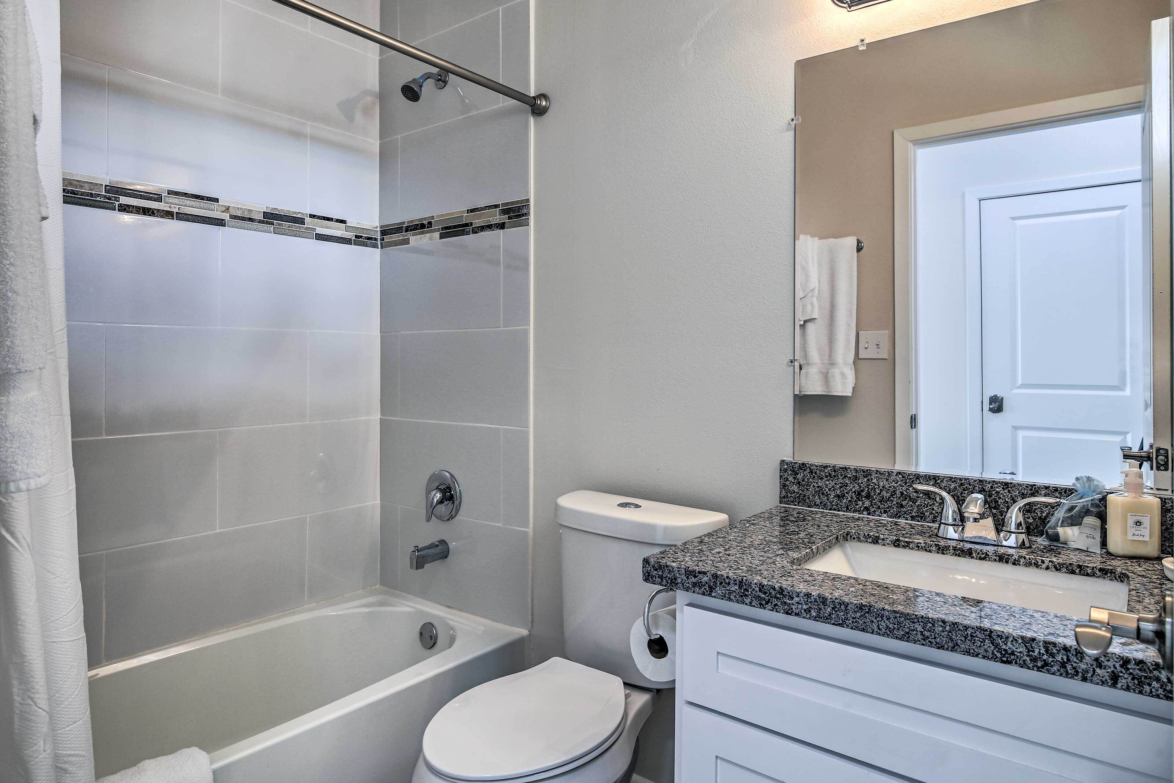 A bathroom with a bathtub, toilet, sink, and a shower curtain.