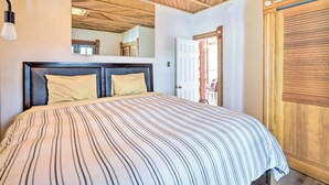 Quarto com uma cama grande, teto de madeira, um espelho e uma porta.