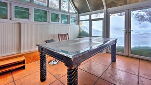 Quarto com uma mesa grande, um banco e amplas janelas com vista para a neve.