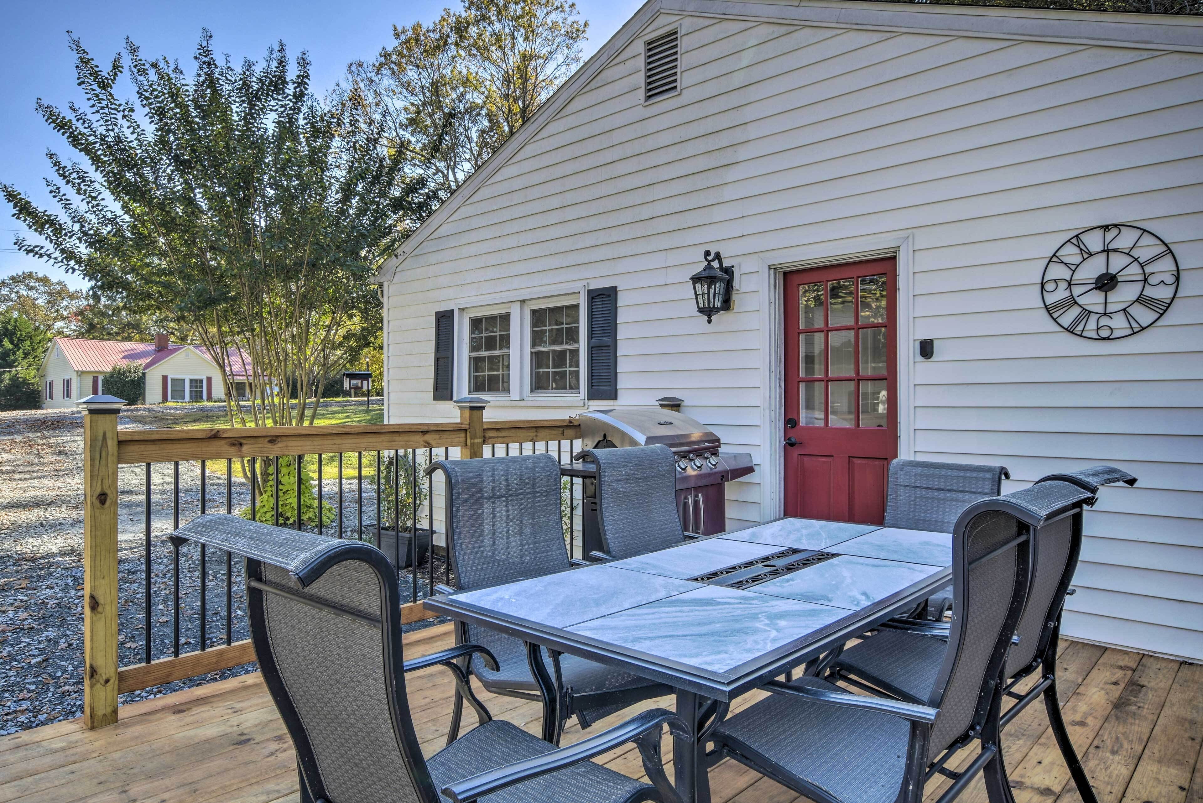Une terrasse couverte avec une table et des chaises, un barbecue et une porte rouge.