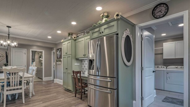 A modern kitchen with a stainless steel refrigerator, wooden dining table, and chairs. - Cedar Falls Country Cottage Near the Zoo! (Randleman)