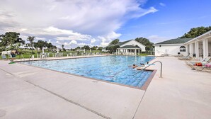 A swimming pool with a clear sky, lounge chairs, and a building in the background. - Ocala Gem: 5 Mi to World Equestrian Center! (Ocala)