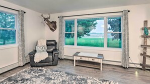 A room with a large window, a leather chair, a small table, and a mounted deer head. - Cozy Seneca Falls Home Close to Cayuga Wine Trail! (Seneca Falls)
