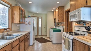 A kitchen with wooden cabinets, a refrigerator, a stove, and a microwave. - Cedar Cottage, Private Beach on Lake Leelanau (Cedar)