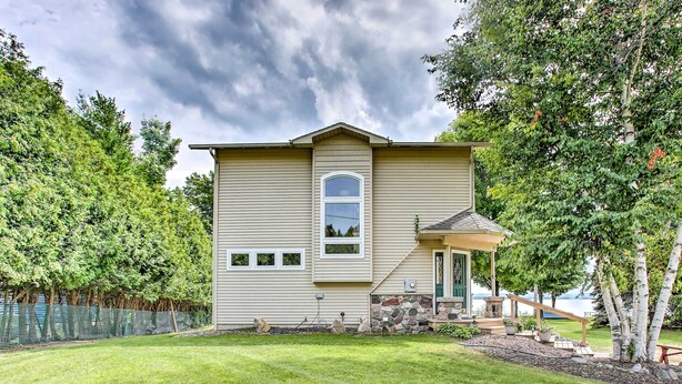A two-story house with a stone foundation, a covered porch, and a view of a lake. - Cedar Cottage, Private Beach on Lake Leelanau (Cedar)