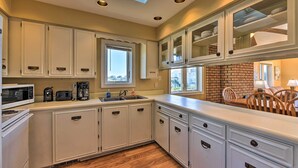 A kitchen with white cabinets, a brick backsplash, and a window.