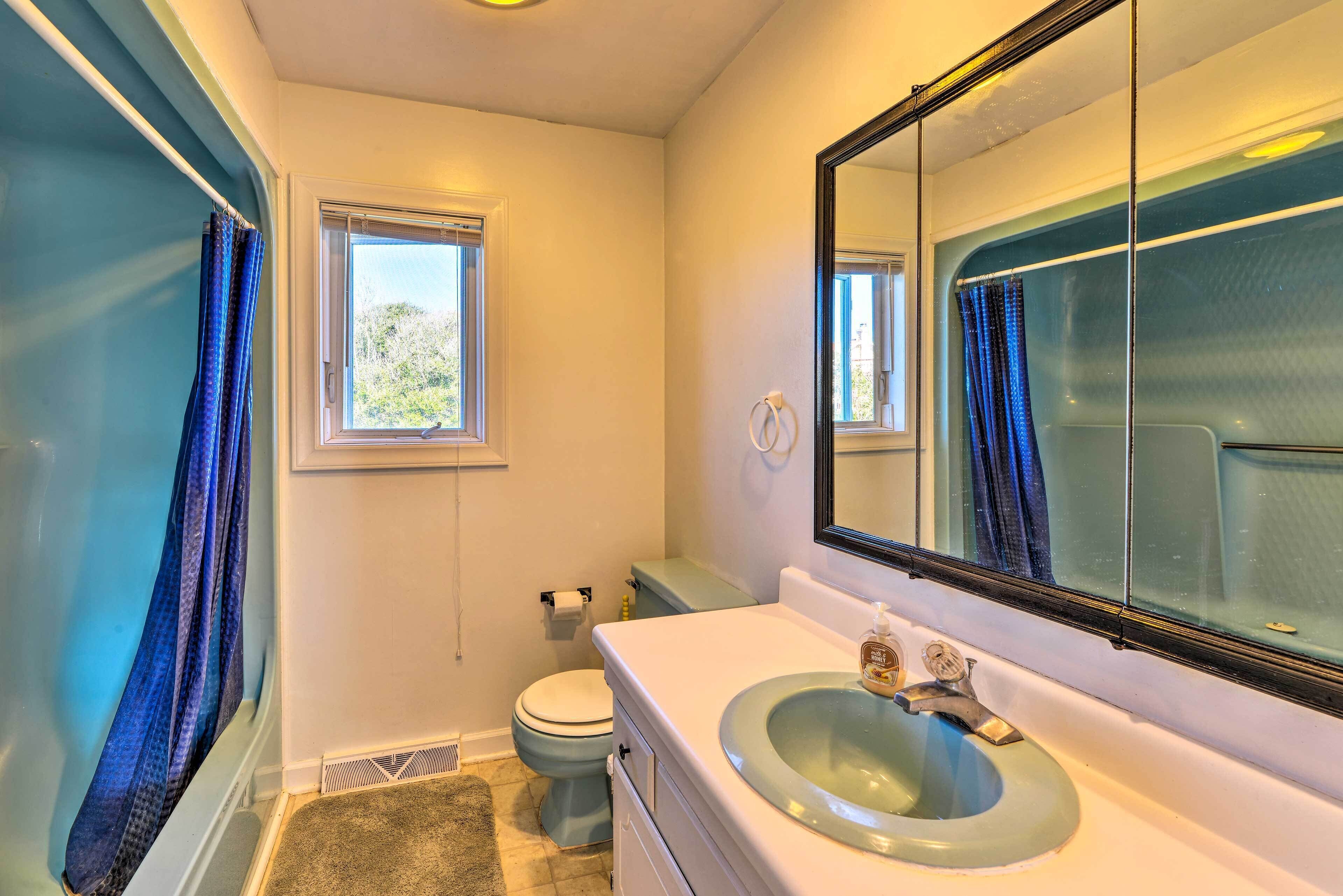 Un baño con bañera, inodoro, lavamanos y un espejo grande.
