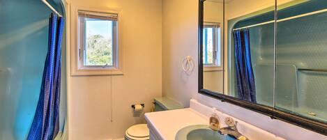 Un baño con bañera, inodoro, lavamanos y un espejo grande.