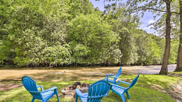 Um camping com quatro cadeiras Adirondack azuis dispostas em volta de uma fogueira.