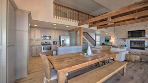 A spacious kitchen with white cabinets, a wooden dining table, and a stone fireplace. - Stunning Lakefront Home: Hot Tub & Game Room! (Mabank)