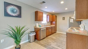 A kitchen with wooden cabinets, a dishwasher, and a potted plant.