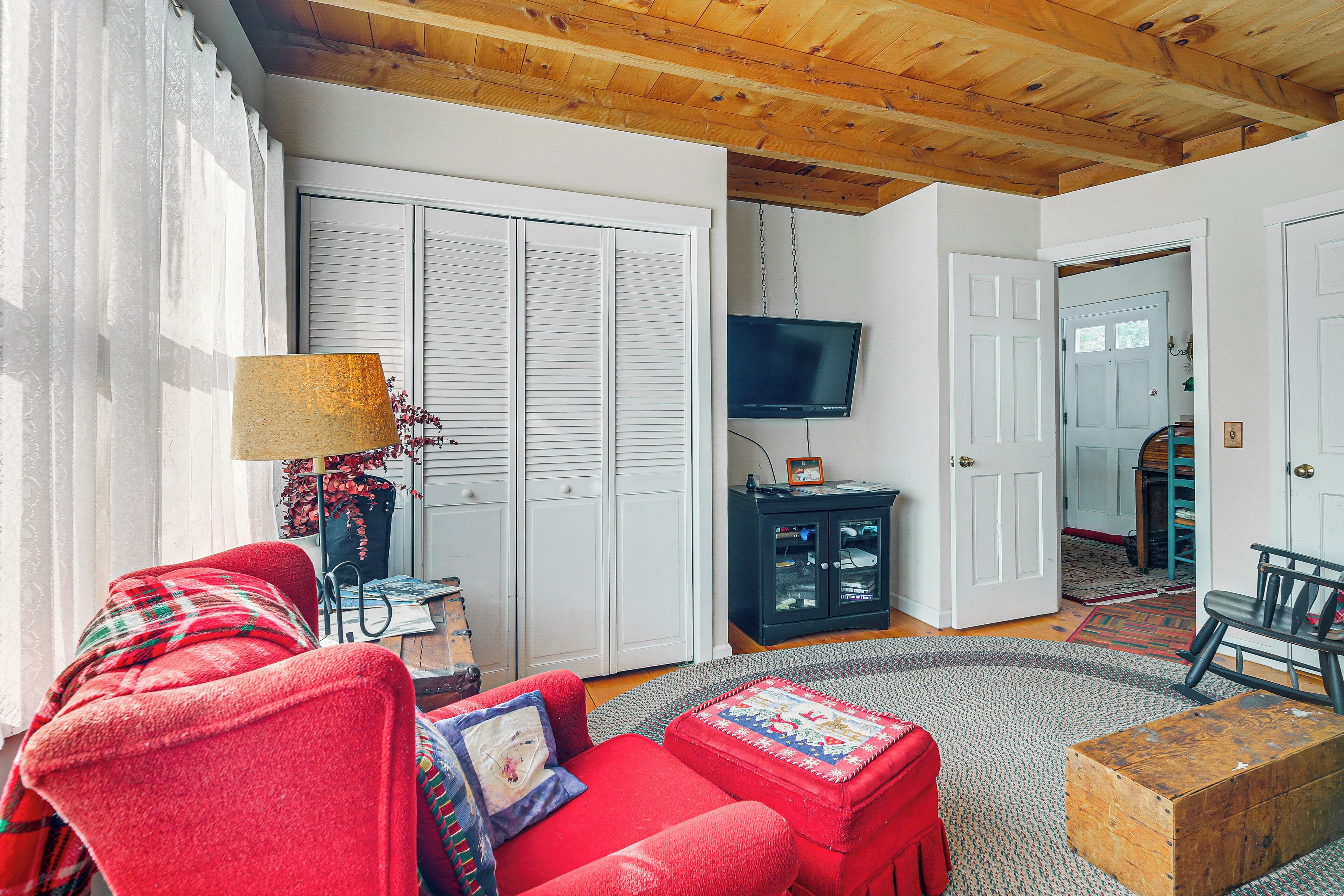 A cozy living room with a red sofa, a wooden coffee table, and a television on the wall.