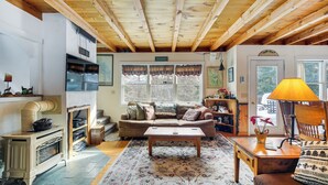 A cozy living room with a wooden ceiling, a fireplace, a sofa, a coffee table, and a lamp. - 4 Mi to Sugarbush Resort: Waitsfield Retreat (Waitsfield)