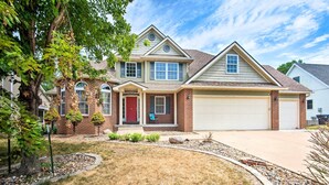 A two-story house with a red front door, a garage, and a well-maintained lawn. - Pet-friendly Des Moines Home w/ Fenced Yard! (Des Moines)