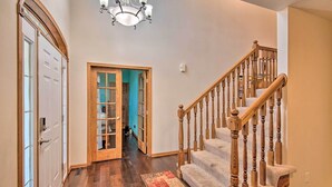 A hallway with a wooden staircase, a chandelier, and a rug. - Pet-friendly Des Moines Home w/ Fenced Yard! (Des Moines)