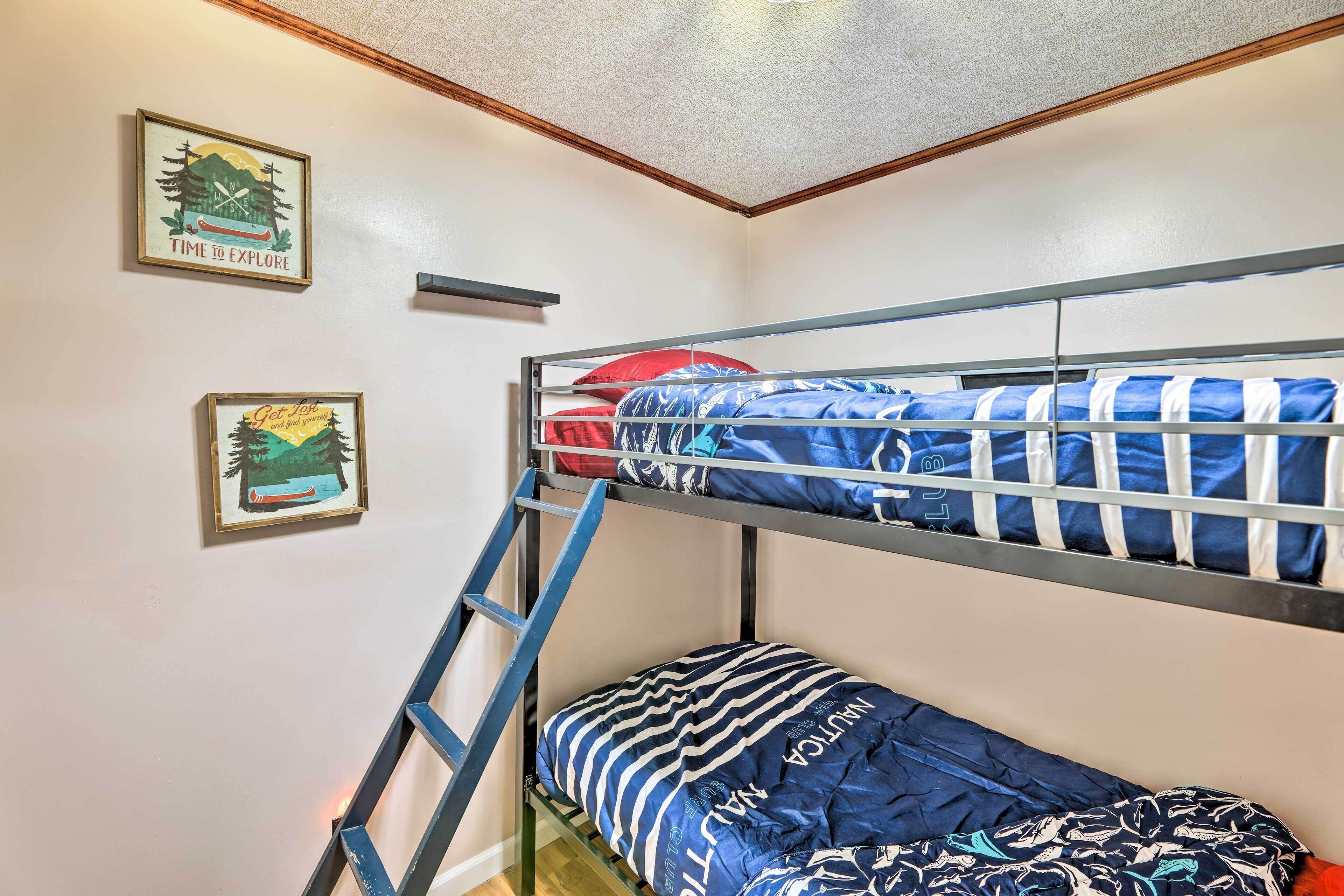 A bunk bed room with a ladder, two framed pictures on the wall, and a bunk bed with blue bedding.