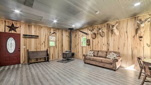 A rustic interior with wooden walls, a bench, a sofa, and mounted animal heads. - Charming New Concord Cabin on 50-acre Farm! (New Concord)