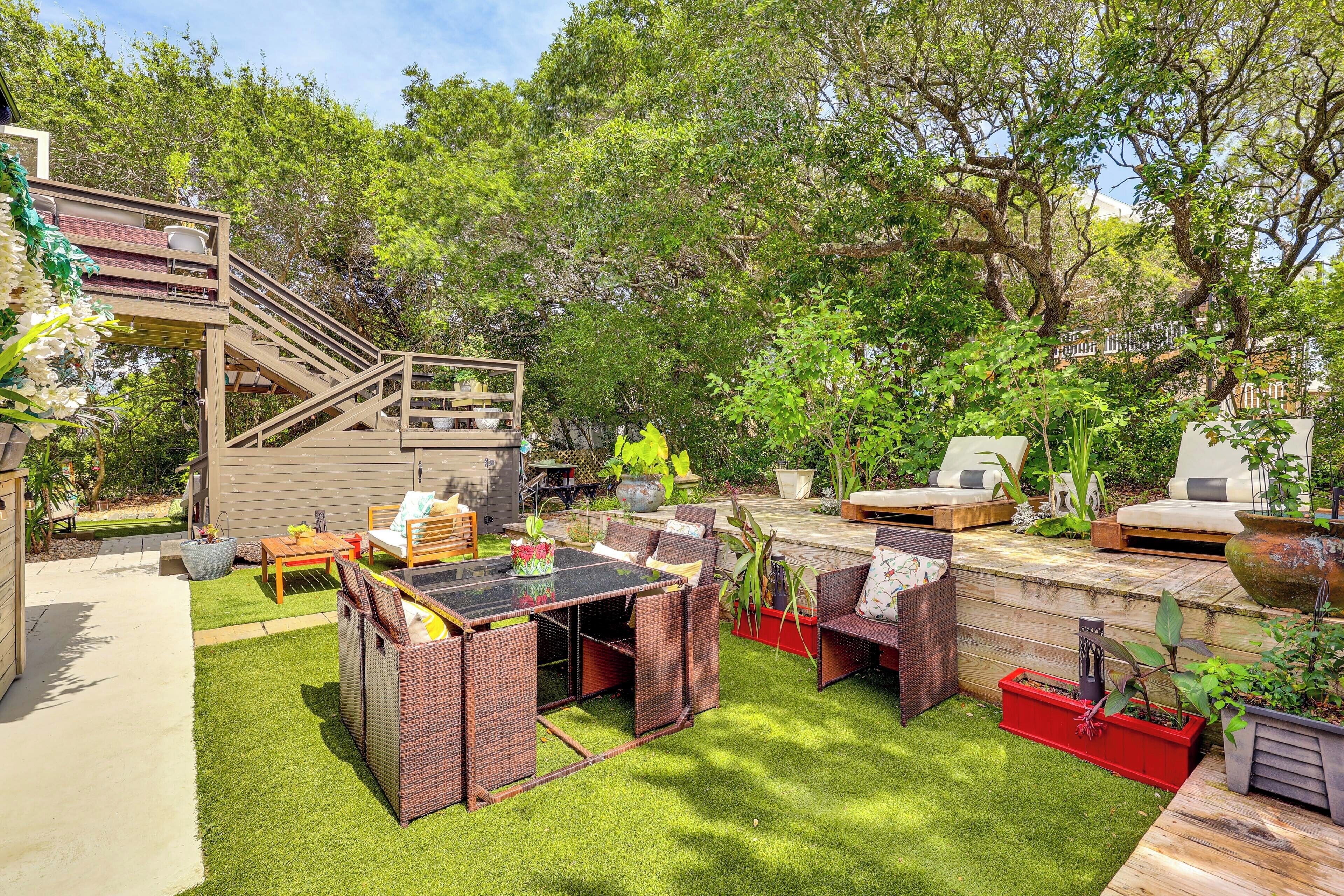 Un jardin avec une terrasse en bois, du mobilier d’extérieur et un petit escalier menant à un niveau supérieur.