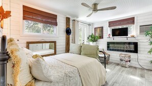 Ein Schlafzimmer mit Bett, Fernseher, Kamin und Deckenventilator.
