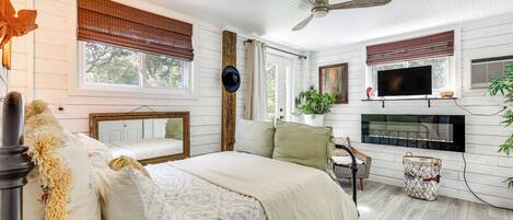 Une chambre à coucher comprenant un lit, une télévision, une cheminée et un ventilateur de plafond.