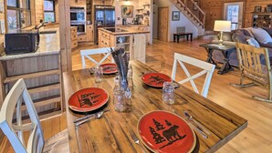 A wooden interior with a dining table set for four, kitchen area, and a staircase.