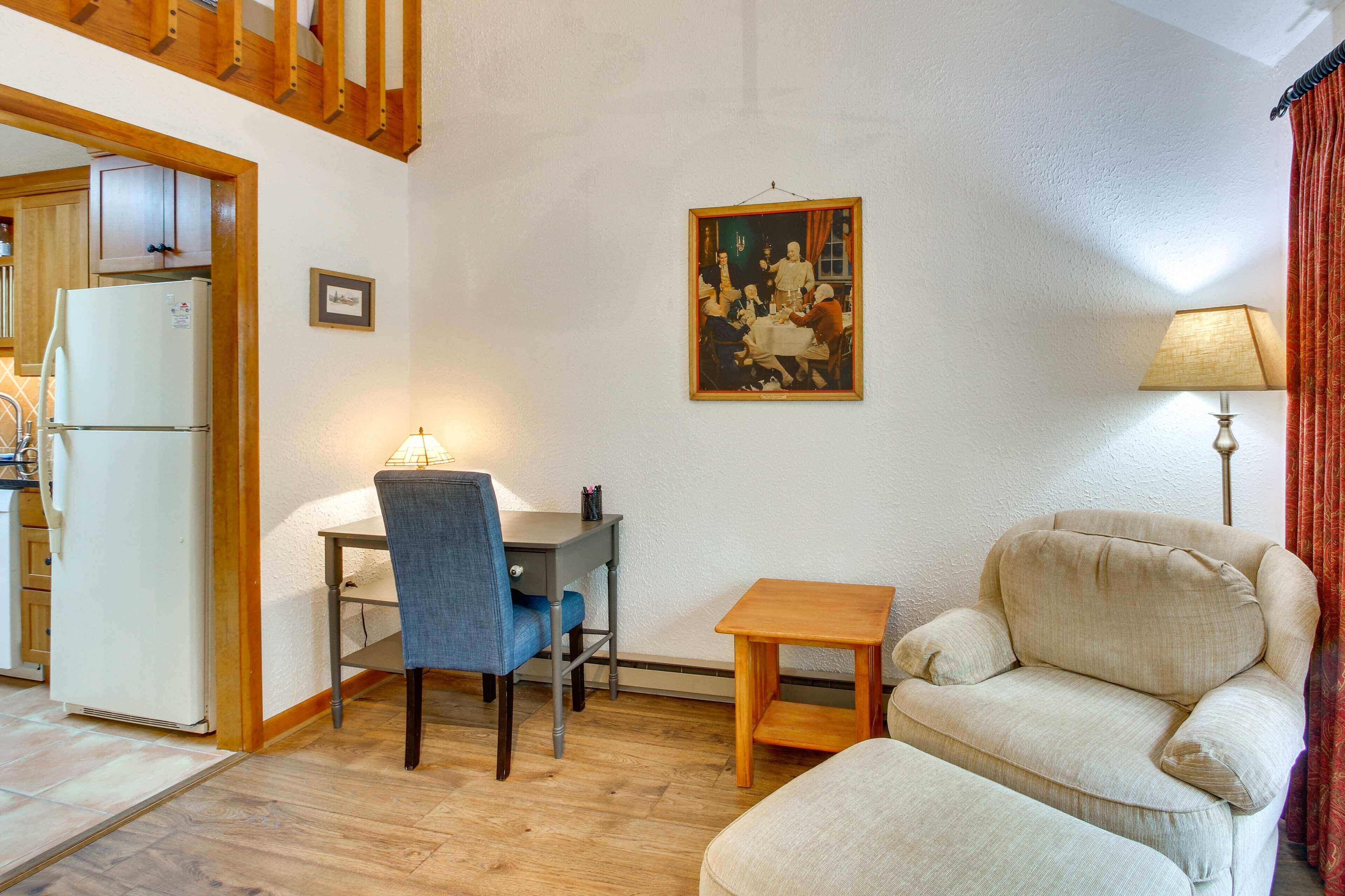A living room with a dining table, a sofa, a small wooden table, and a lamp.