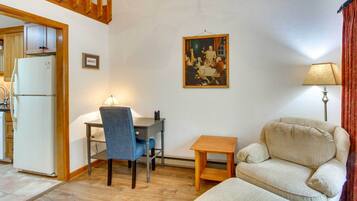 A living room with a dining table, a sofa, a small wooden table, and a lamp.