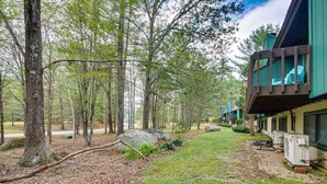 A building with a deck area, surrounded by trees and a grassy path. - 1 Mi to Downtown Conway: Spacious Family Condo! (North Conway)