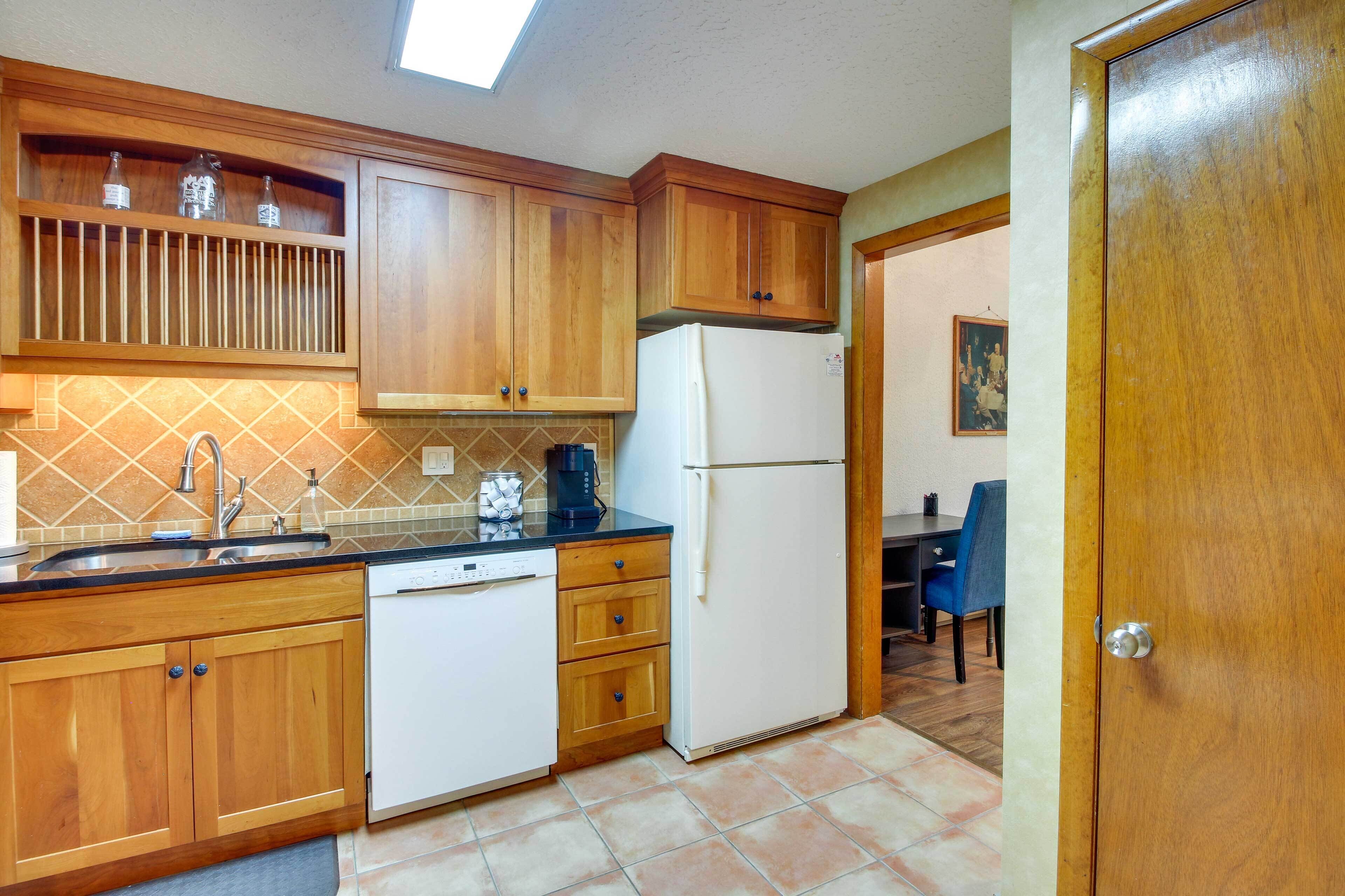 A kitchen with wooden cabinets, a white dishwasher, and a refrigerator.