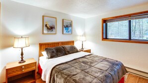 A bedroom with a bed, two bedside tables with lamps, a window with a view of trees, and two framed pictures on the wall. - 1 Mi to Downtown Conway: Spacious Family Condo! (North Conway)