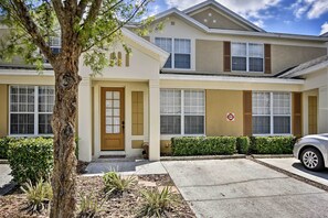 Un immeuble résidentiel de deux étages, avec une façade beige, une porte d’entrée et une porte de garage.
