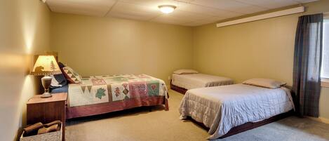 A bedroom with two beds, a nightstand, a lamp, and a small basket.