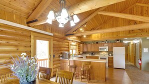 A wooden cabin interior with a dining area, kitchen, and bar.
