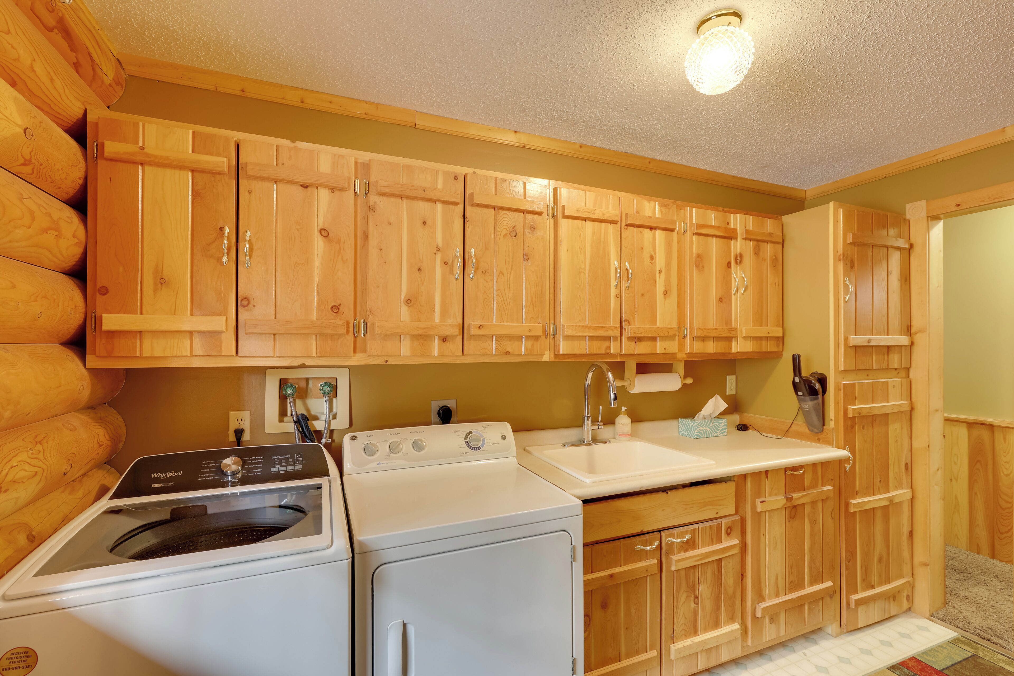 A compact kitchen with wooden cabinets, a built-in washer and dryer, a sink, and a countertop.