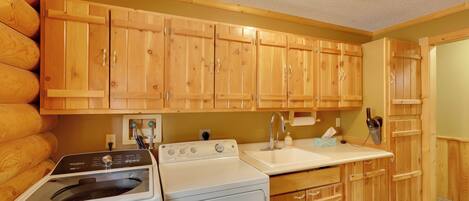 A compact kitchen with wooden cabinets, a built-in washer and dryer, a sink, and a countertop.
